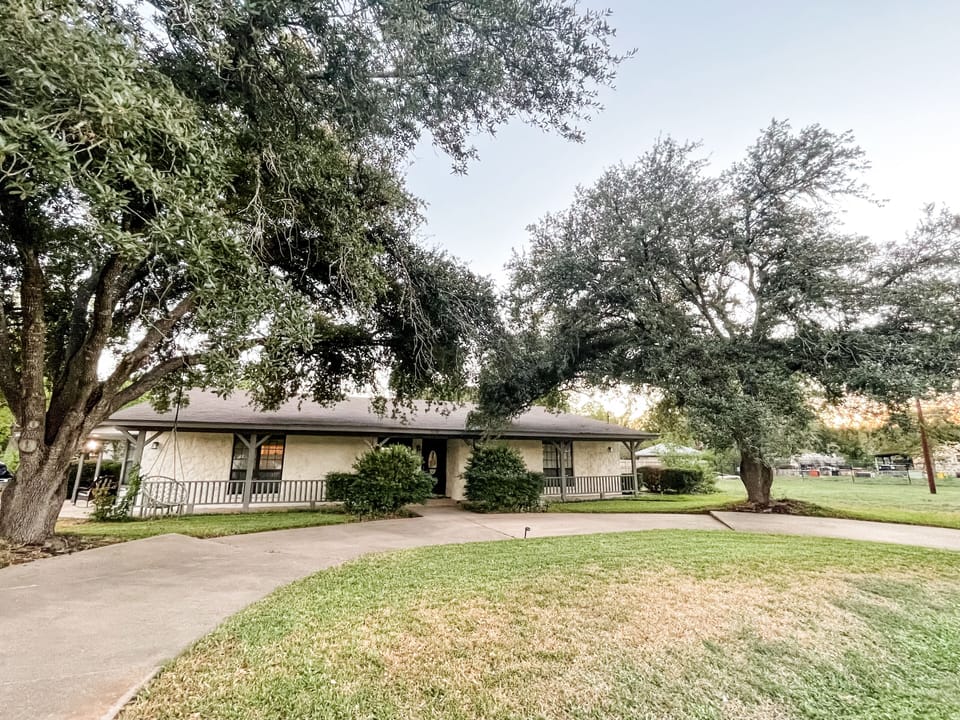 Front view with boho swing hanging on 2 giant oak trees with circular driveway.