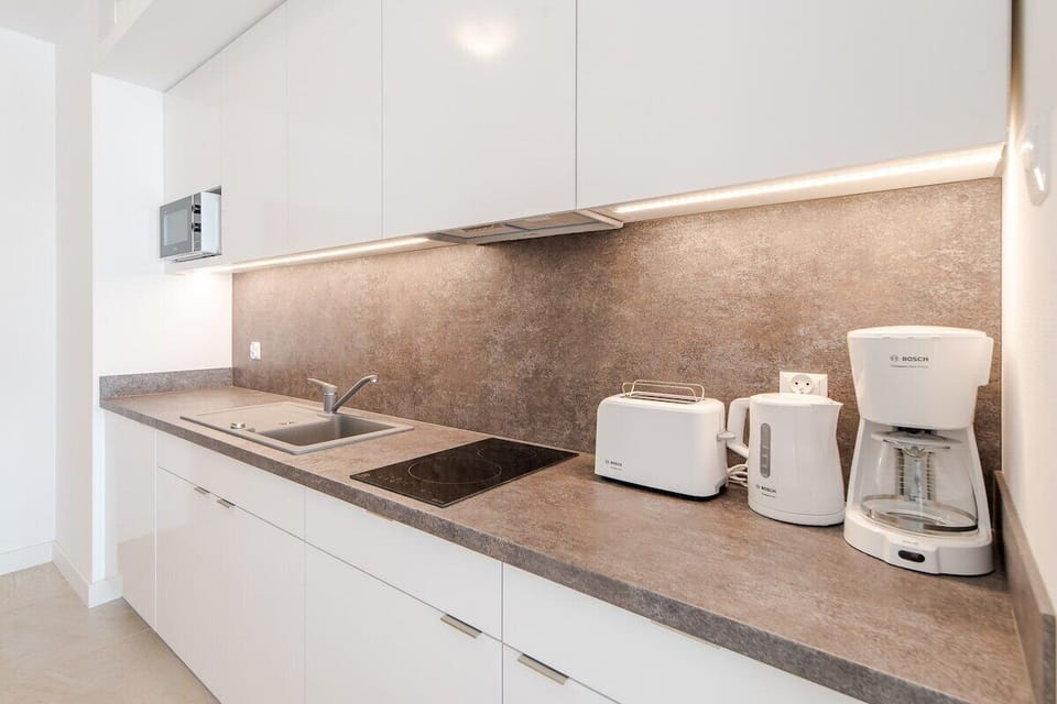 A modern kitchen with white cabinetry, built-in appliances, and sleek stone countertops for a functional and clean design.

