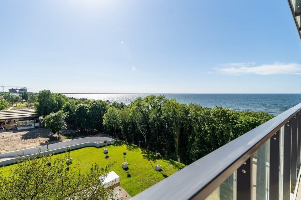 A wide perspective of the view from the balcony, highlighting the surrounding greenery and water.

