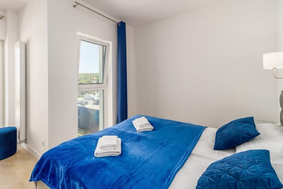Another angle of the bedroom, showcasing large windows with curtains, allowing natural light to fill the space.
