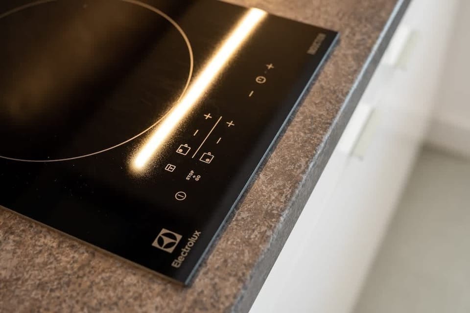 A sleek induction cooktop on a gray countertop, emphasizing a modern and minimalist kitchen design.
