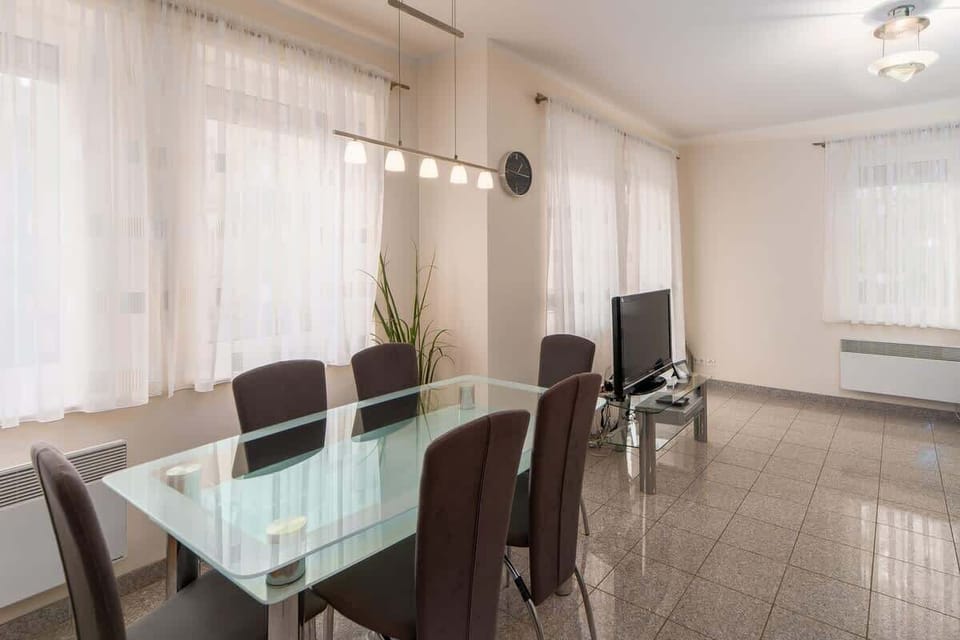 A dining area with a glass table and chairs, situated near large windows for natural light.
