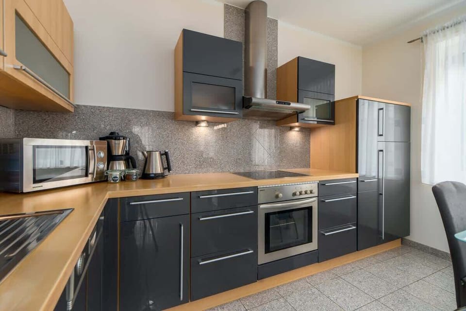 A modern kitchen with dark cabinets, a wooden countertop, and integrated appliances, blending style and functionality.
