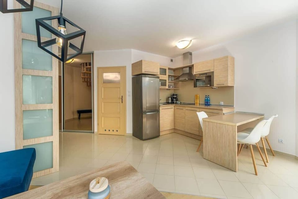 An open-plan kitchen and dining area with wooden cabinetry and a small dining table, blending functionality with style.
