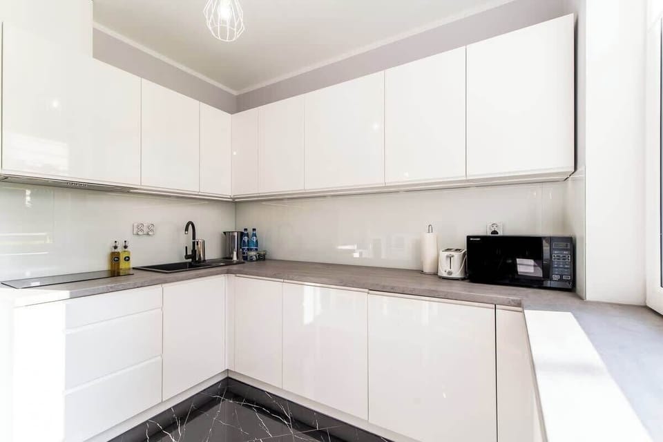 A close-up of the kitchen corner, highlighting the black countertop and white cabinets for a stylish contrast.
