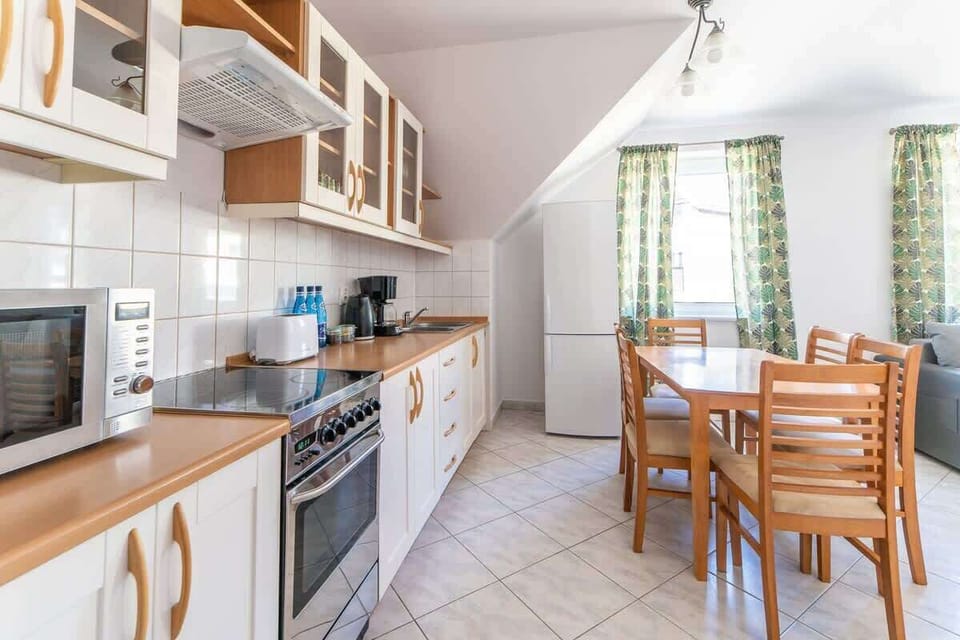 A well-equipped kitchen with wooden cabinetry, white tiles, and modern appliances.

