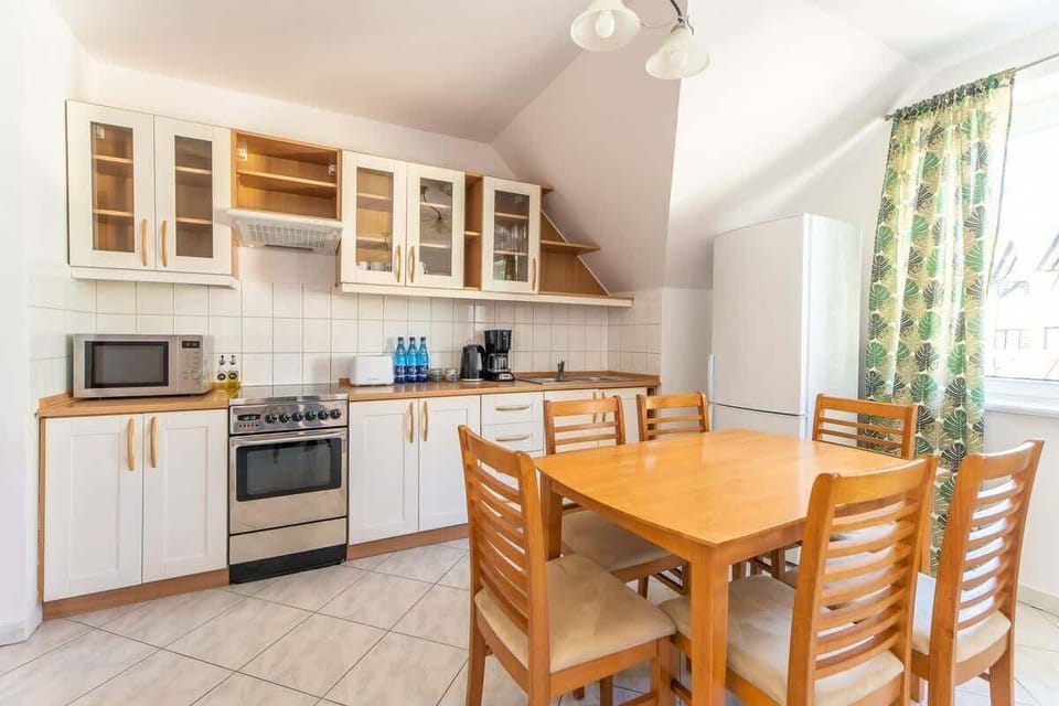 A spacious kitchen-dining area with wooden furniture, tiled floors, and plenty of natural light.

