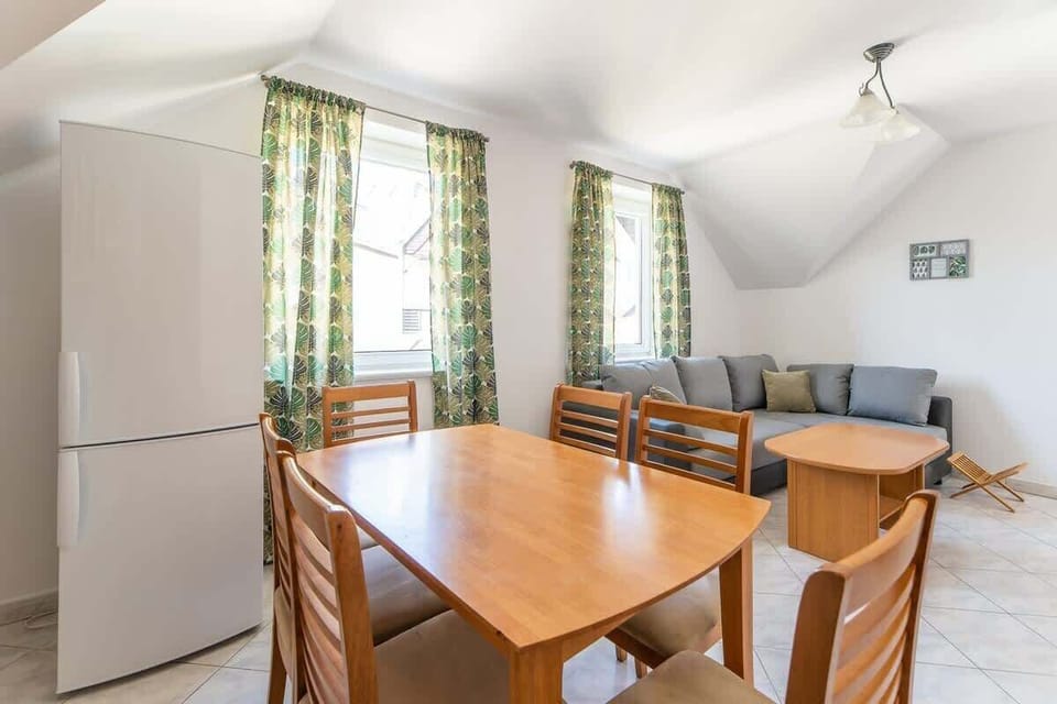 Another view of the dining area, showcasing the wooden table, chairs, and bright curtains.

