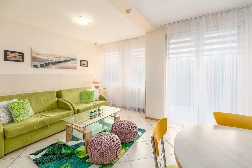 Another angle of the living room, highlighting the green sofa, natural light, and cozy decor.

