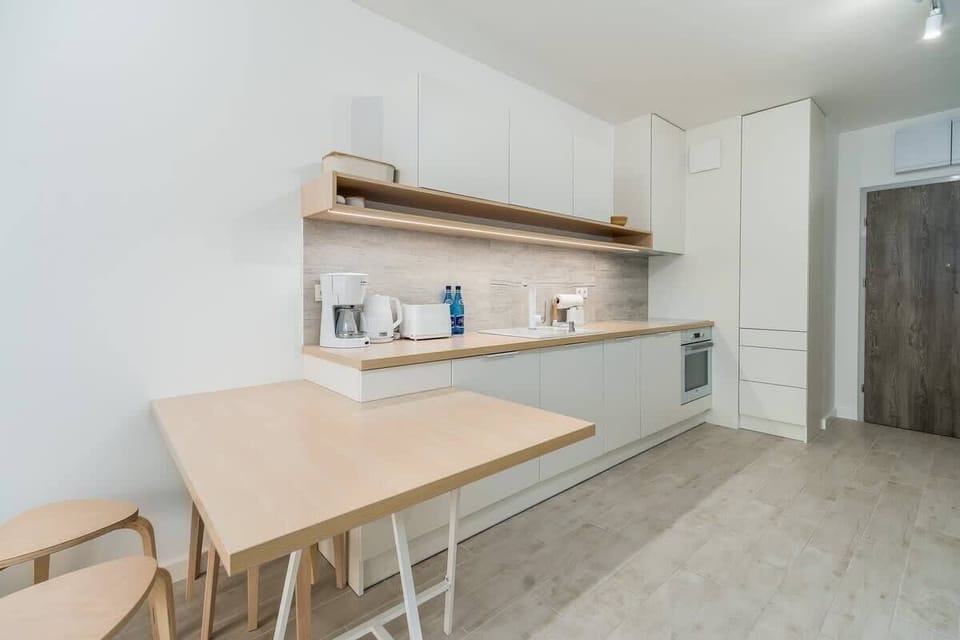 A dining area adjacent to the kitchen, featuring a light wooden table and matching chairs.
