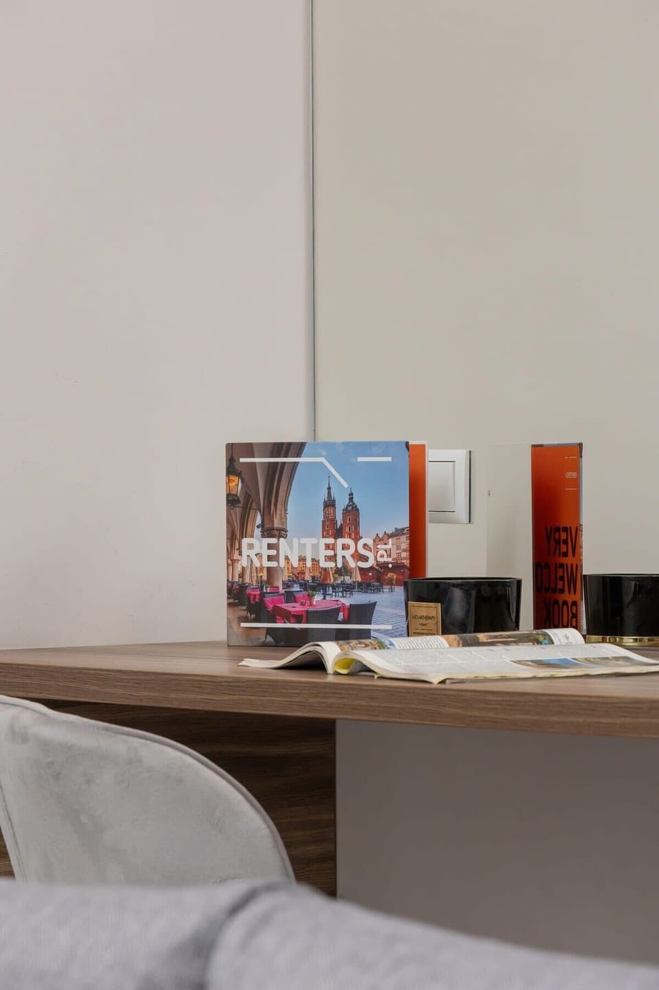 A desk corner displaying brochures and a small decorative element against a neutral background.
