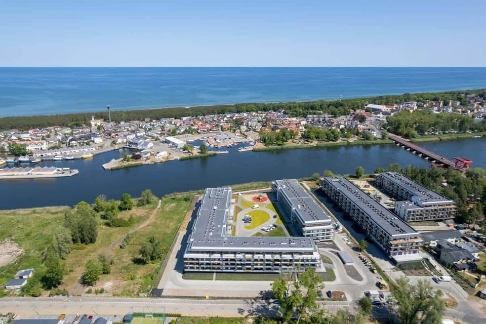 Aerial view of a residential complex, emphasizing its proximity to the water and surrounding nature.
