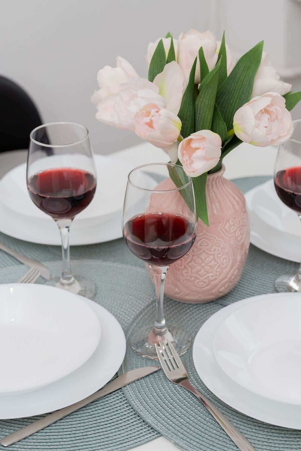 A close-up of a table setting with wine glasses, tulips, and elegant tableware.
