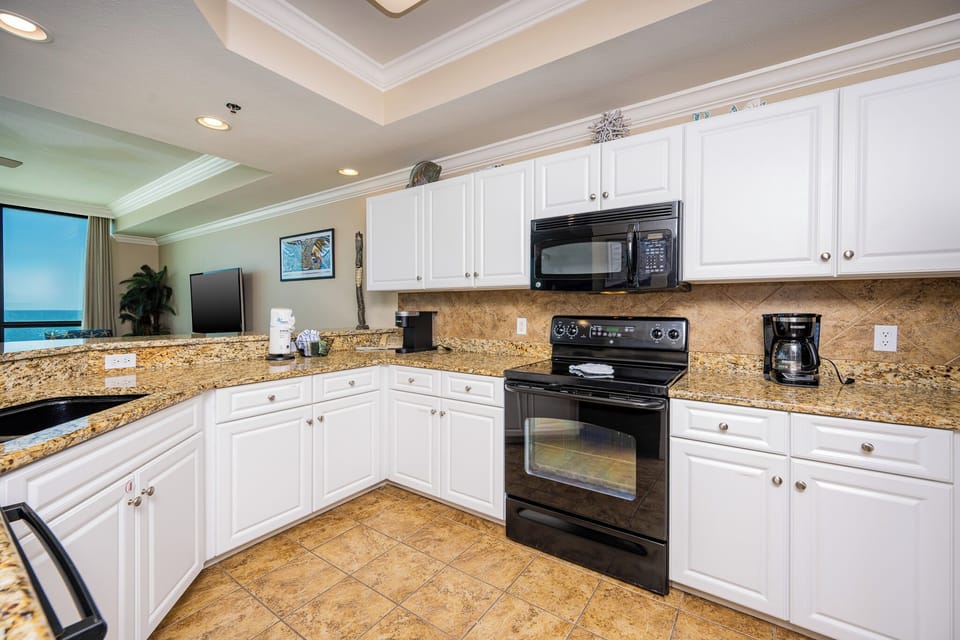 Cook and socialize in the spacious kitchen featuring granite countertops, black appliances, Keurig, and coffee maker