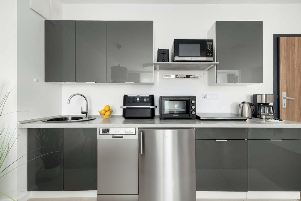 A minimalist kitchen with gray cabinets, stainless steel appliances, and clean countertops.