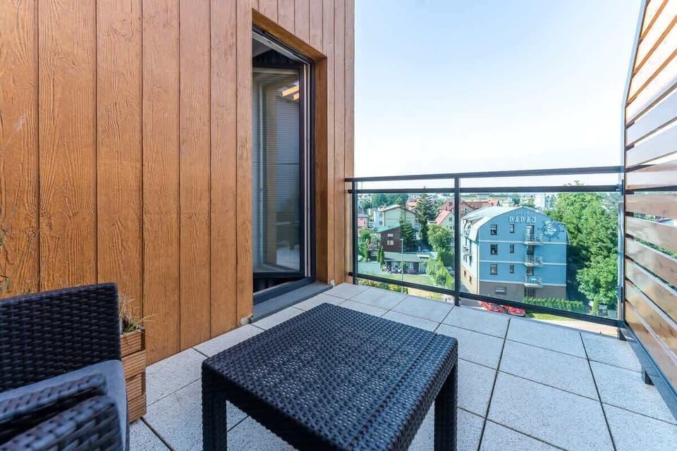 Another perspective of the balcony showcasing modern furniture, privacy panels, and scenic surroundings.
