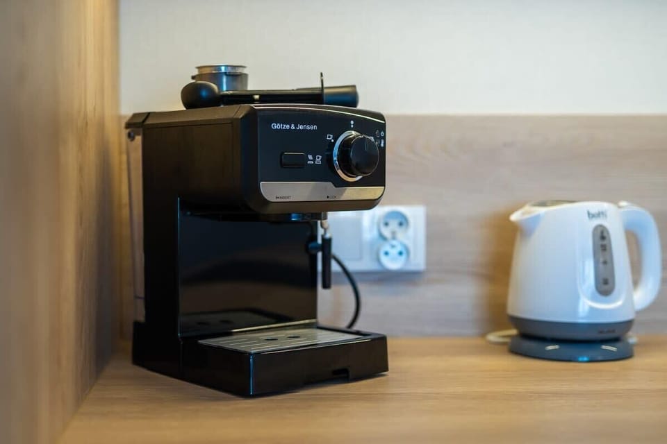 A close-up of a coffee station with a coffee maker and kettle placed on a wooden countertop, providing convenience and style.
