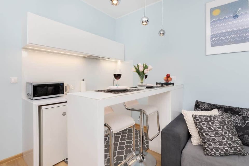 A kitchenette with white cabinetry, a small dining table, and subtle décor for a clean, modern look.






