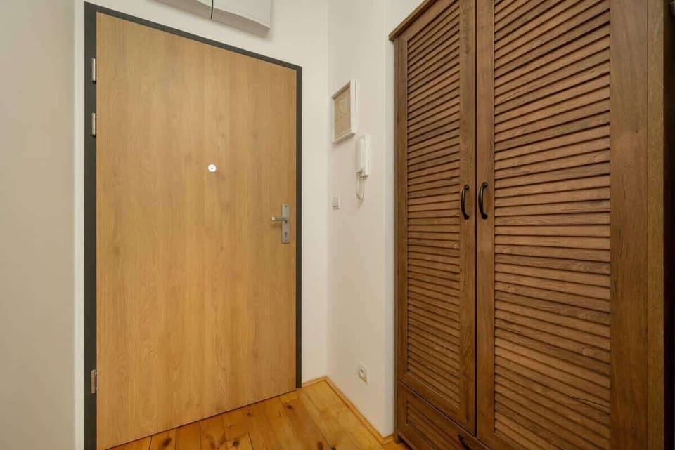 An apartment entrance featuring a wooden door, a wardrobe, and practical storage.
