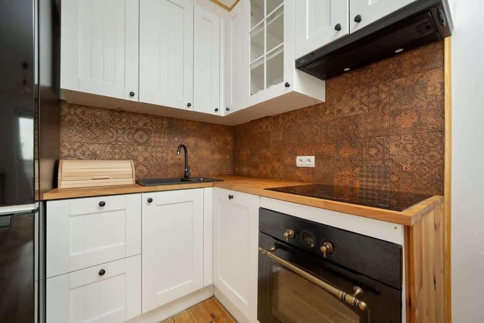 A modern kitchen with a wooden countertop, tiled backsplash, and built-in appliances.
