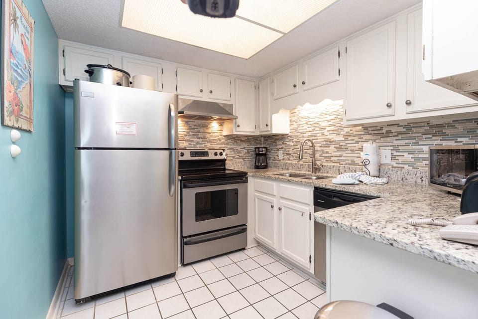 The kitchen features stainless appliances, granite countertops, coffee maker, and a stylish backsplash