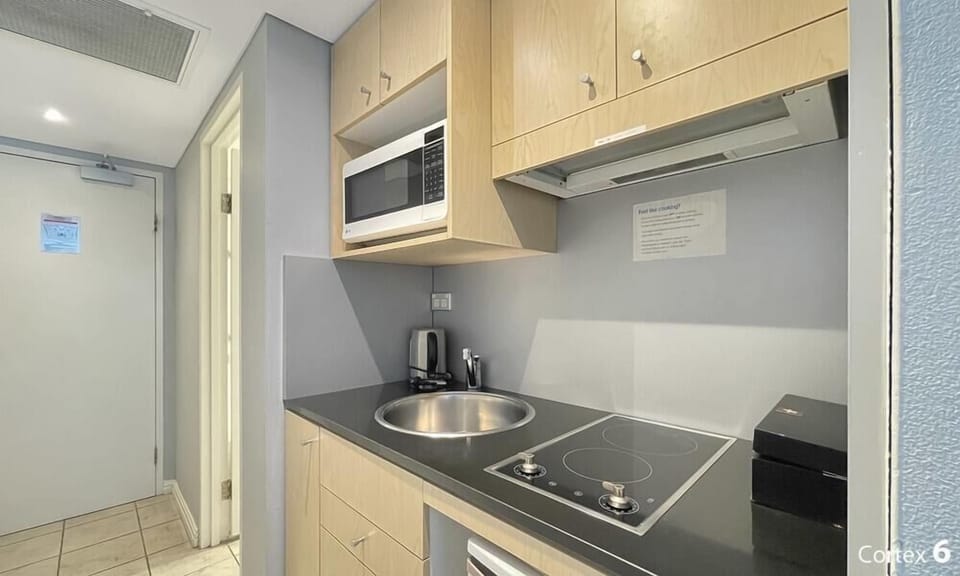 Compact kitchen with cooktop, sink, microwave, and essential appliances.