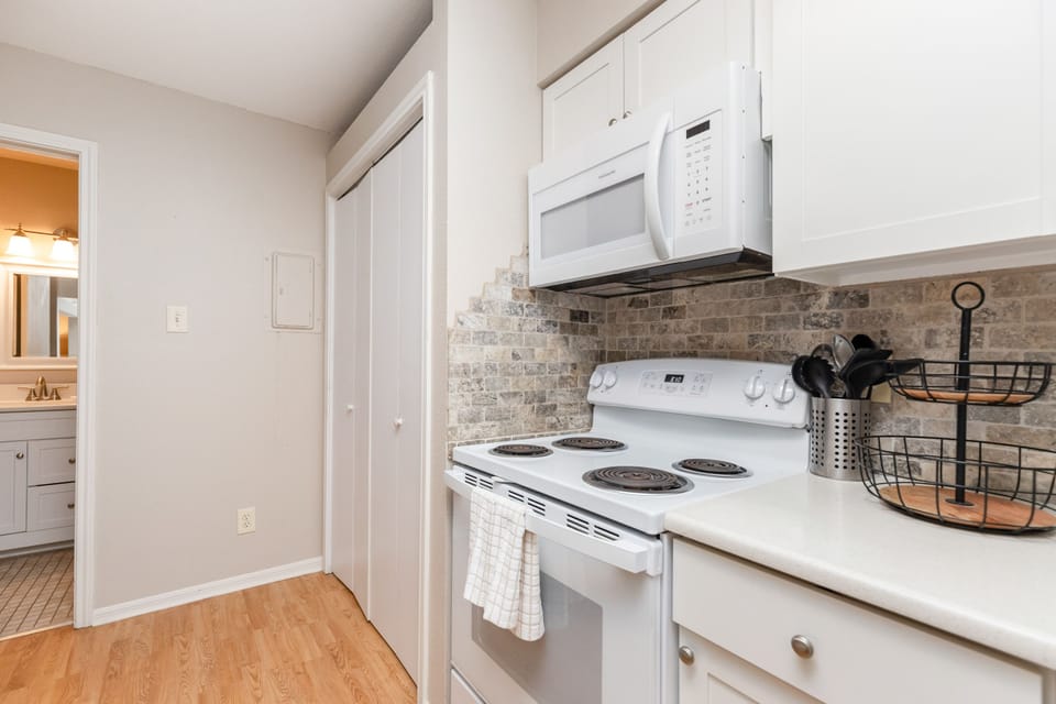 Your fully equipped kitchen awaits with crisp white cabinets, stone-tile backsplash, and modern appliances for easy meal preparation.