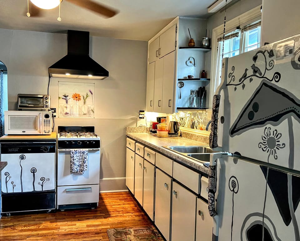 Kitchen with gas stove, coffee maker, electric kettle, microwave, toaster oven.