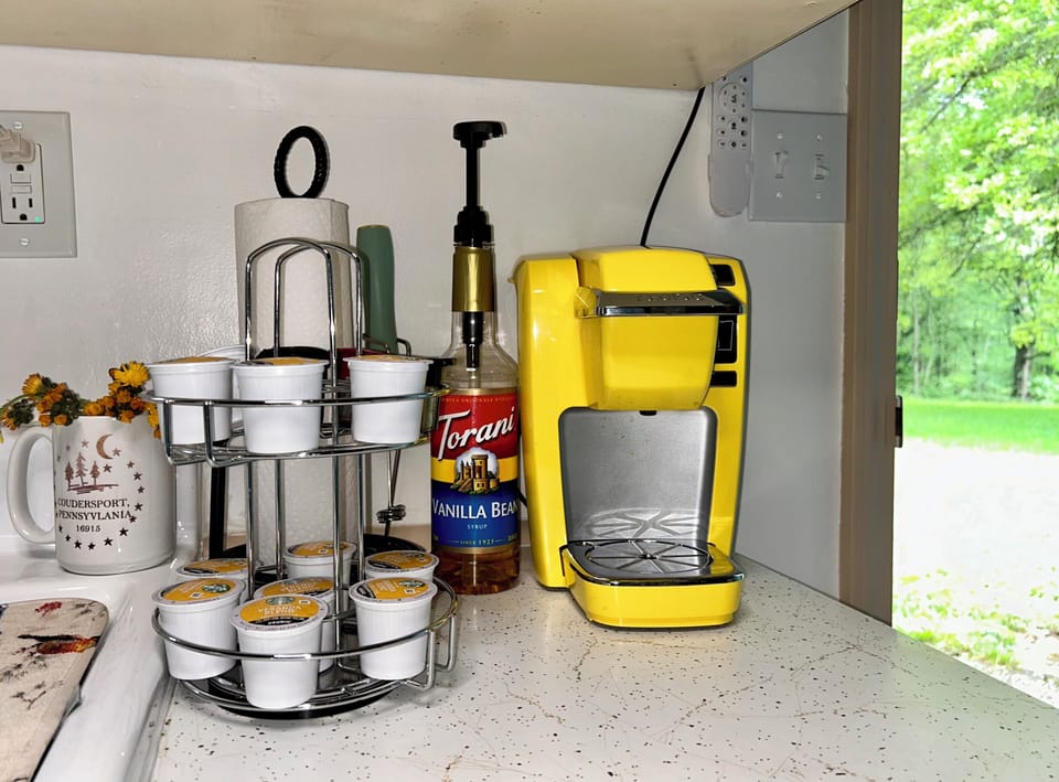 1 cup Keurig, K-cups, mugs above. French press + drip coffee maker in cabinet.
