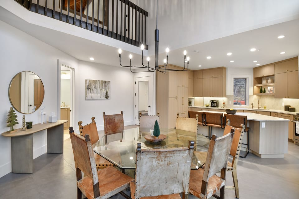 Elegant dining area with rustic leather chairs, modern chandelier, and open flow to the chef's kitchen—perfect for shared meals and conversation (6 Chairs)