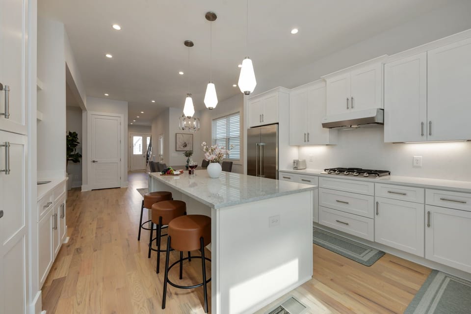 (1st Floor) Fully-equipped kitchen with stainless steel appliances, basic cooking essentials, and kitchen island seating.