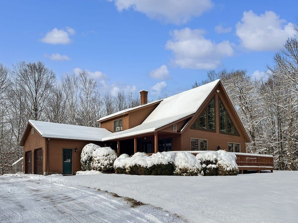 Snowy winter view of the home and wraparound deck.