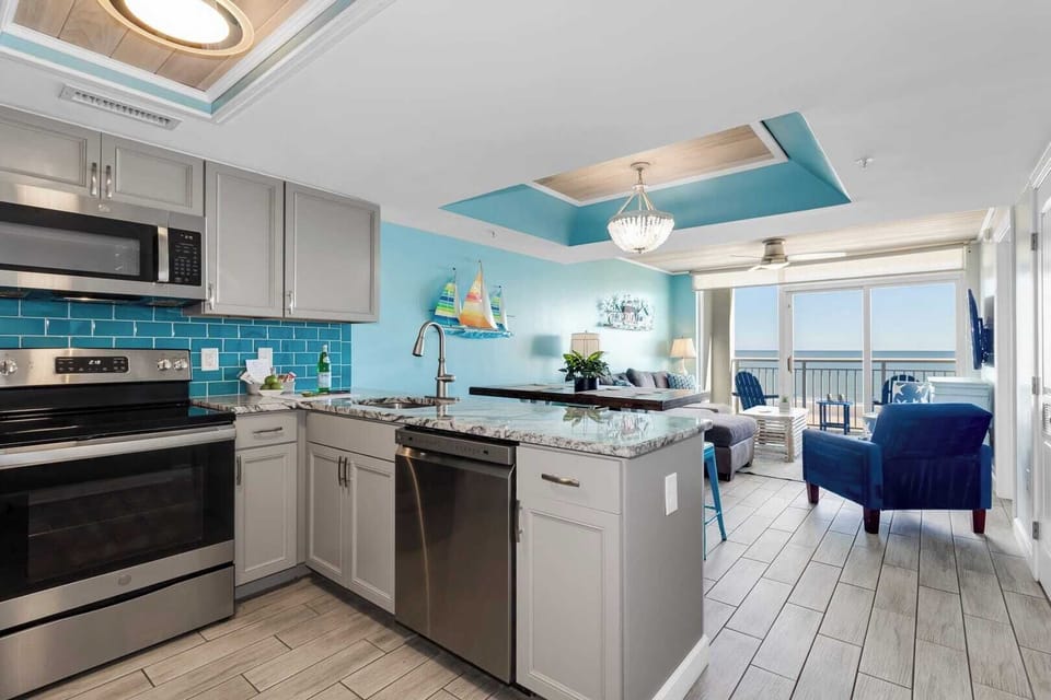 Whip up your favorite meals in this beautifully designed kitchen, featuring modern appliances, stunning blue accents, and granite countertops. Whether cooking or relaxing in the cozy living area with ocean views, this space offers the perfect blend.