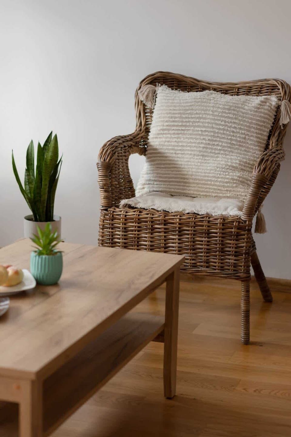 A cozy corner with a wicker chair, a small table, and decorative cushions.






