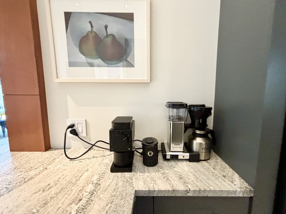 A kitchen counter with a picture of pears on the wall.