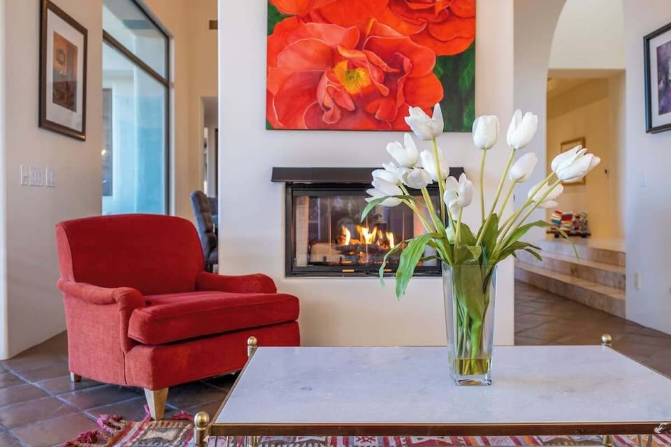 Unwind in your cozy living space, where vibrant art and a warm fireplace invite you to relax with fresh flowers and soft seating.