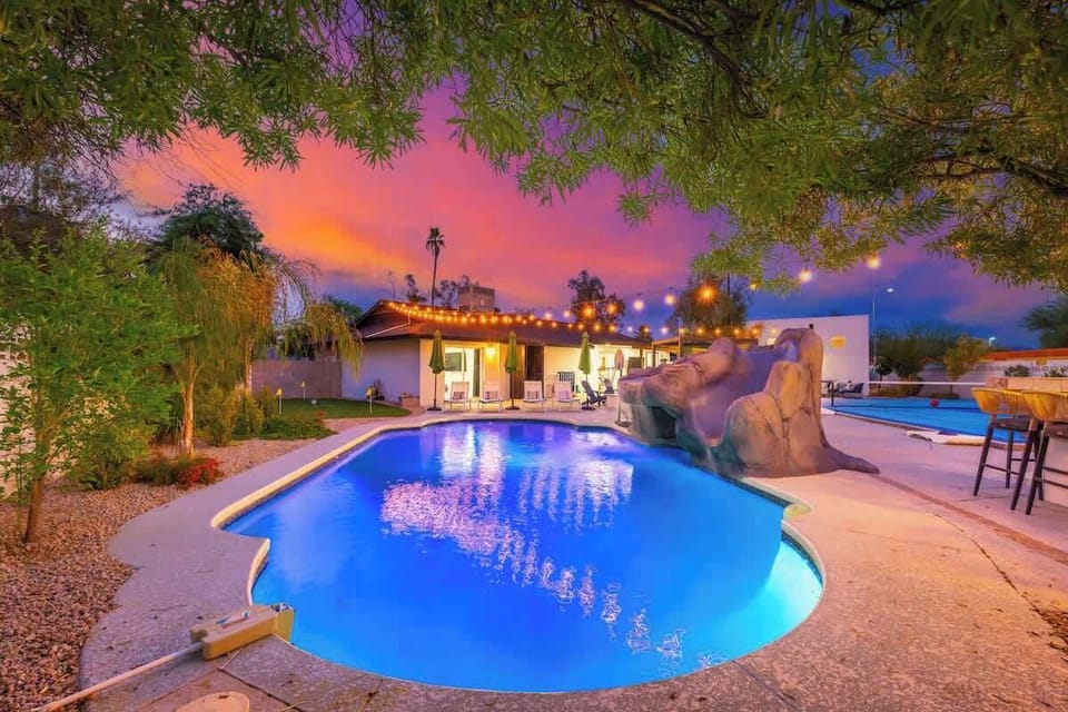 Stunning backyard oasis with illuminated pool framed by desert palms and a vibrant twilight sky, perfect for memorable evenings under the stars.