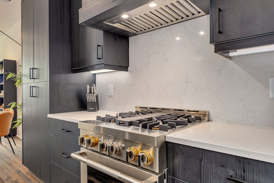 Gourmet gas range w/ modern hood & clean backsplash for easy cooking
