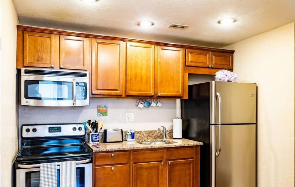 The kitchen is equipped with essential appliances like a refrigerator, oven, microwave, and dishwasher. Additionally, it features elegant shelves and cabinets for efficient storage.
