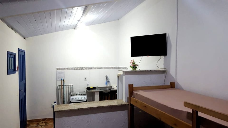 Quarto com TV e cozinha americana