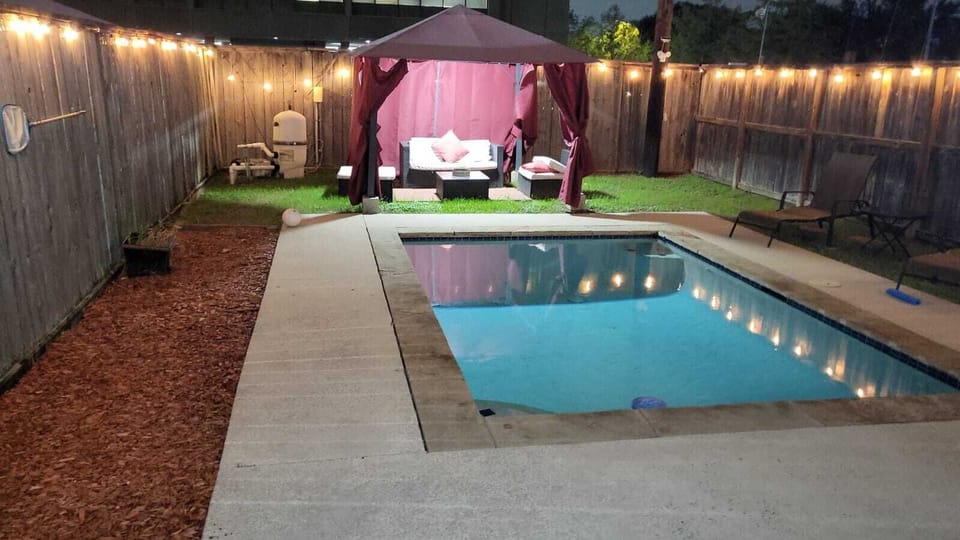 Backyard pool area featuring cabana seating and privacy fence view