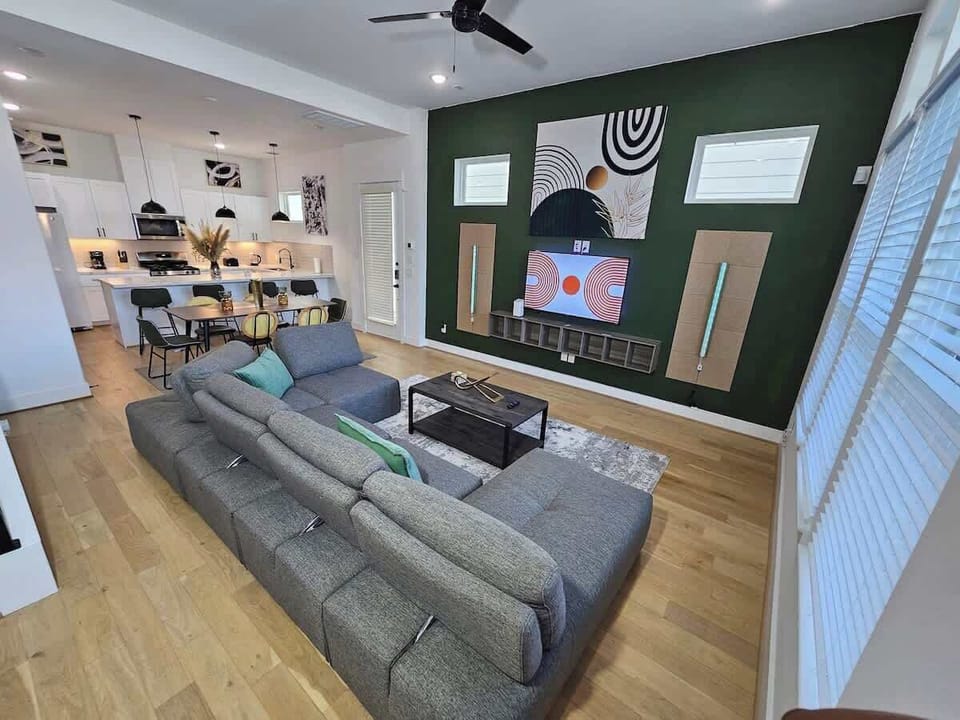 "Elegance shines with natural light in our open-concept living space. Mid-Century Modern charm, a green accent wall, and a 55" TV await."