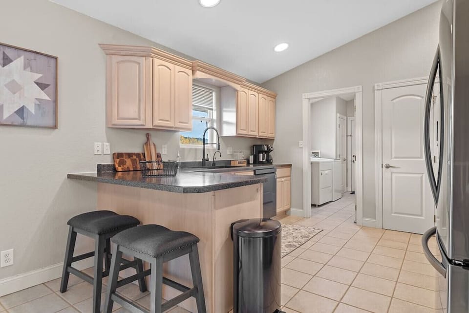 Enjoy a modern and practical kitchen design with a spacious countertop and stools for a convenient and stylish dining area.