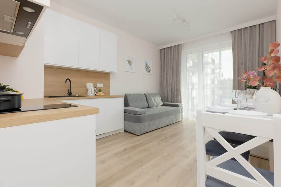 An open-plan living space with white cabinets, wooden accents, and a comfortable seating area.
