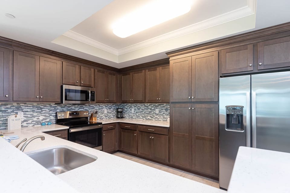 Prepare meals in this sleek kitchen with a vibrant backsplash, stainless appliances, and rich cabinetry