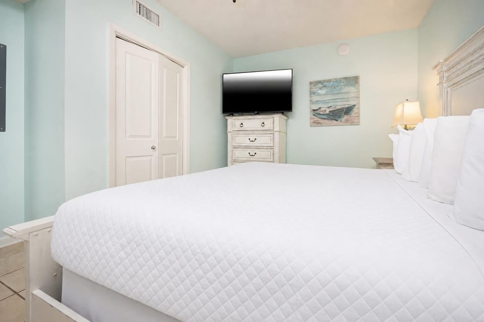 Inviting bedroom featuring a king bed, a TV for entertainment, and soft blue walls for a calming atmosphere
