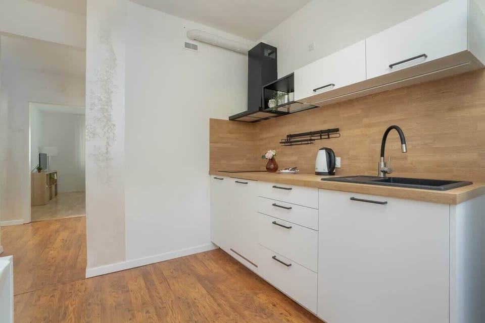 A modern kitchen with white cabinets, a wooden countertop, and integrated appliances.
