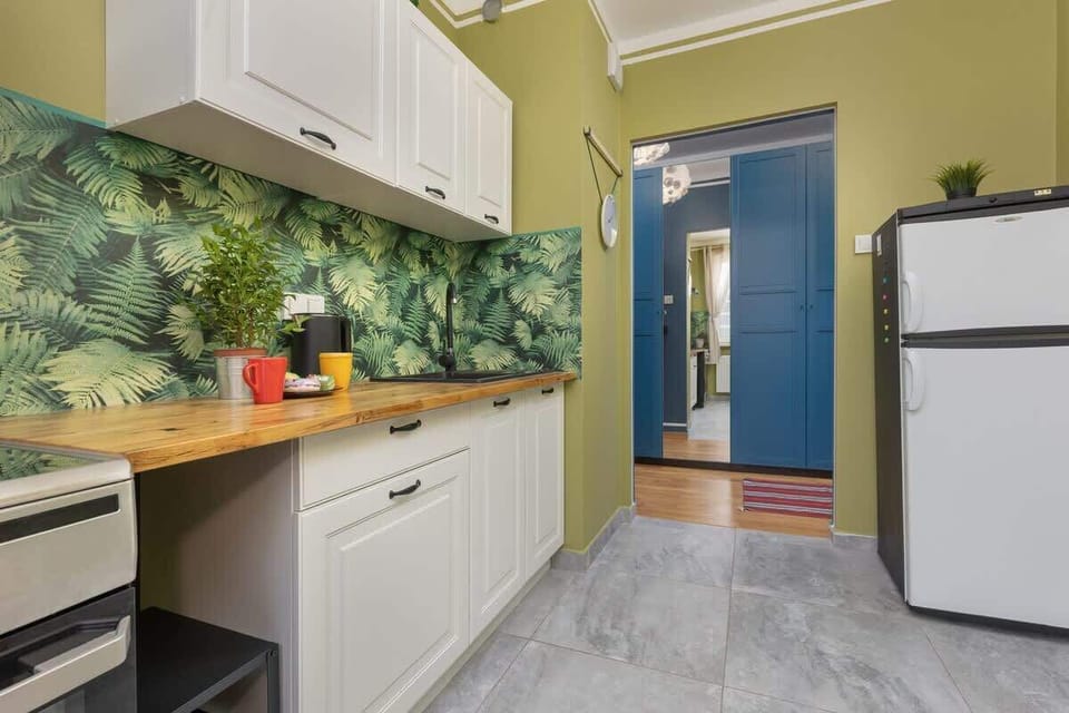 A different perspective of the kitchen, showing a tropical-themed backsplash and white cabinets.
