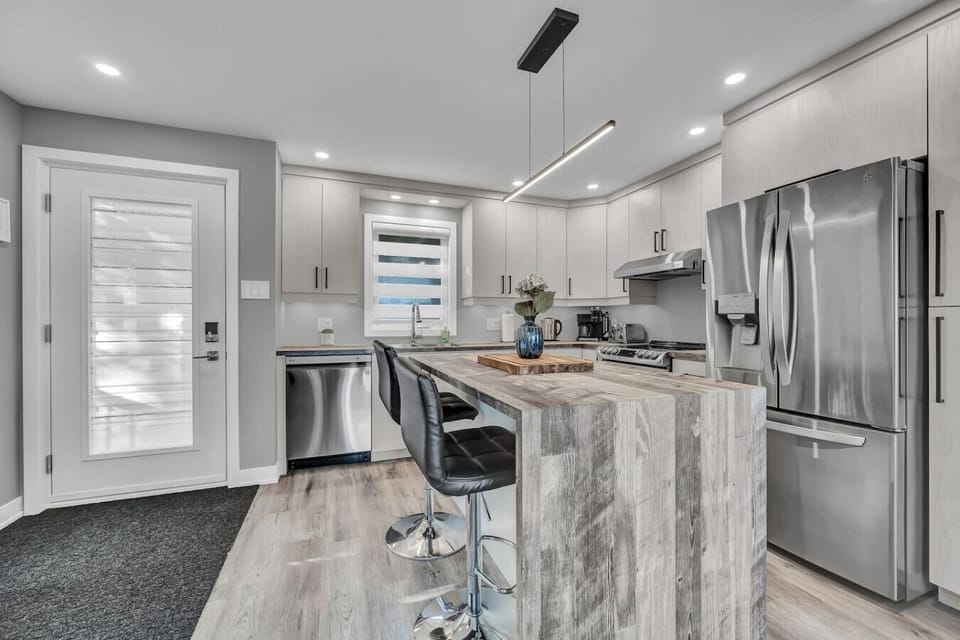 Fully equipped kitchen with stainless steel appliances, large island, and breakfast bar seating.