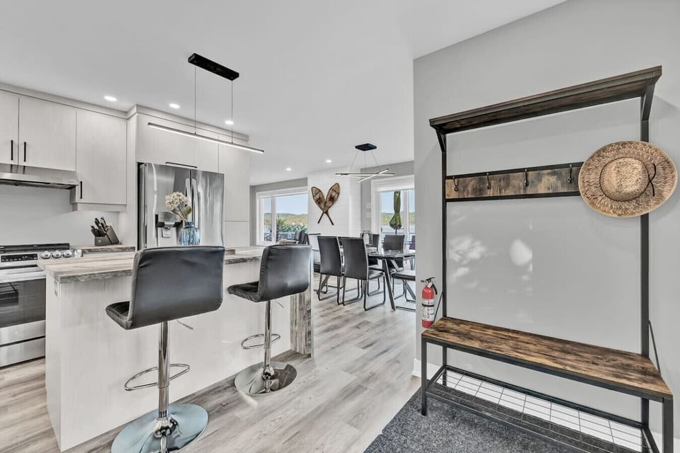 Open-concept kitchen with bar seating, stainless steel fridge, and direct access to the dining area.